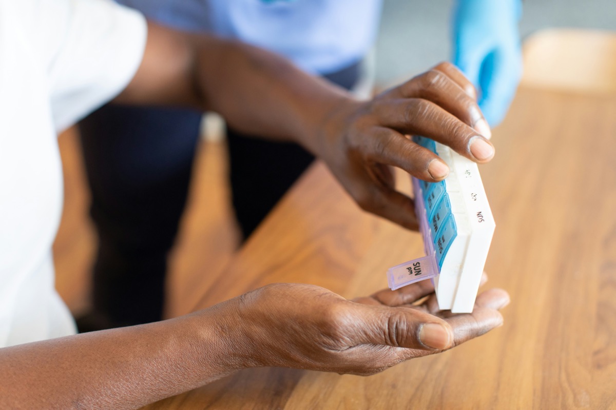 A caregiver helping a resident with a weekly medication organizer